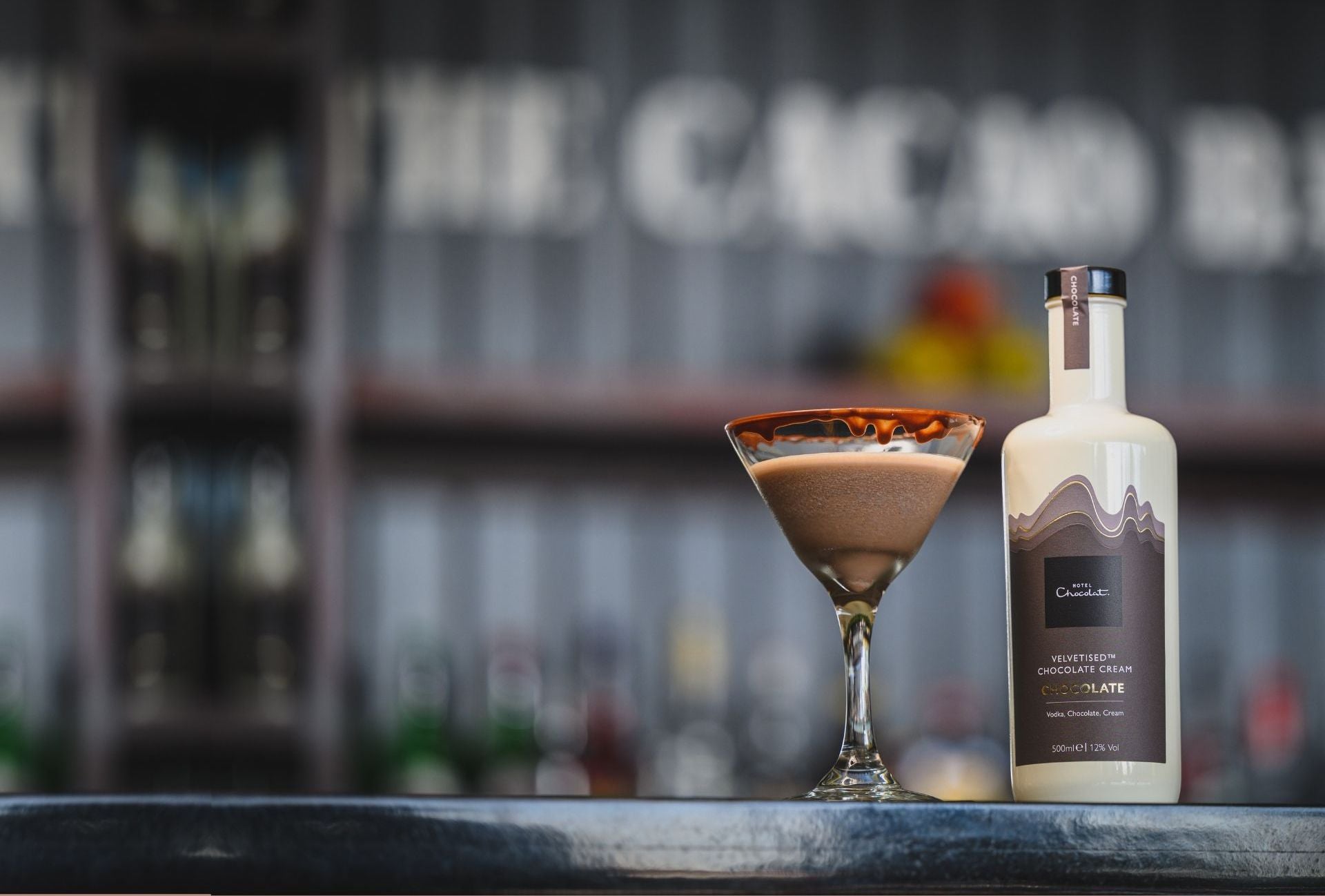 A chocolate martini sits on a bar, next to a bottle of Hotel Chocolat's velvetised cream liqueur.