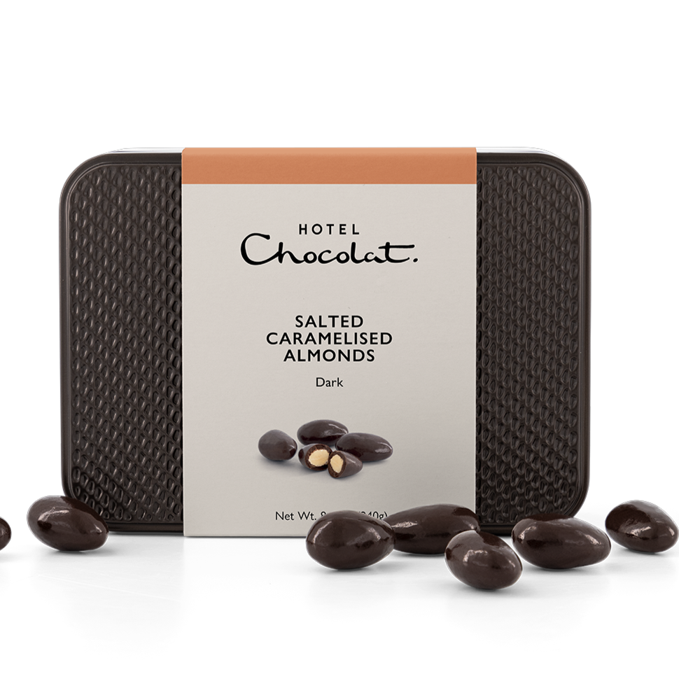 Dark Chocolate Covered Salted Carmelised Almonds piled in front of tin. 